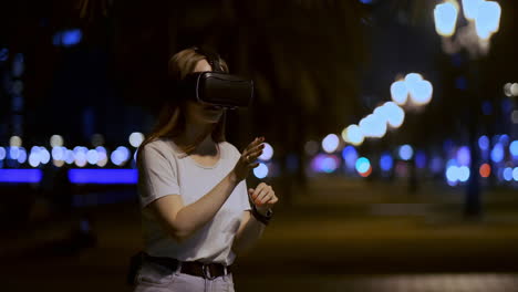 A-young-girl-in-virtual-reality-glasses-in-a-large-metropolis-simulates-work-in-the-program-game-virtual-reality-interface.-The-concept-of-augmented-reality